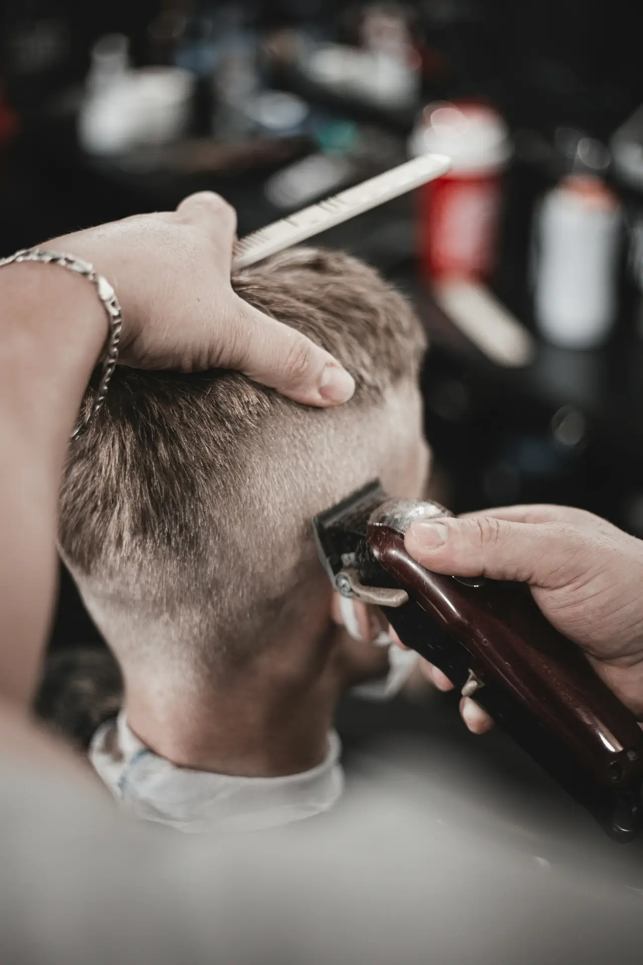 Barbero repasando un degradado con máquina en la nuca de un cliente