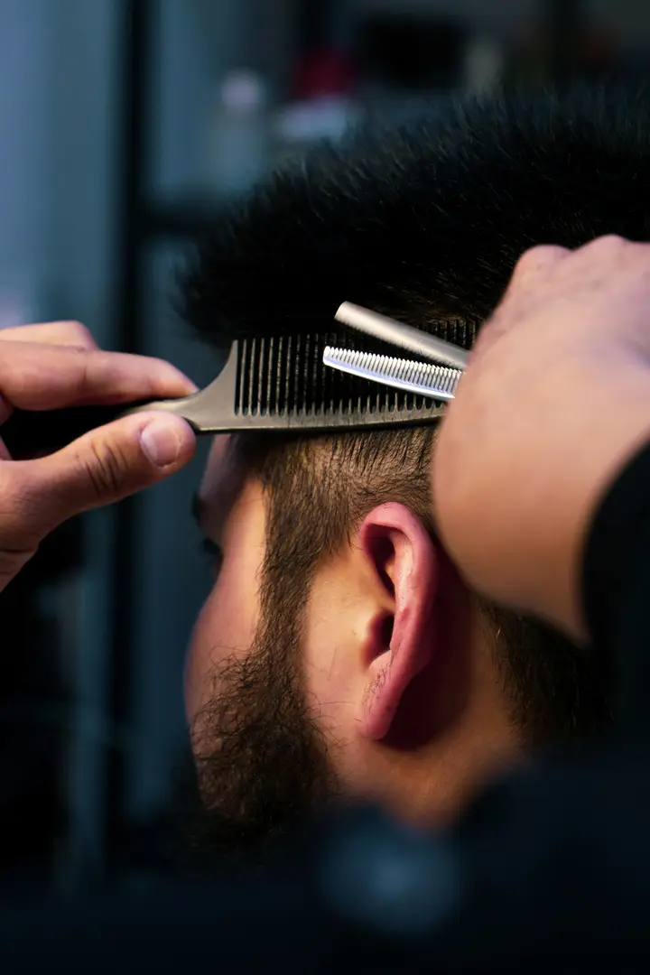 Barbero entresacando el pelo con tijera y peine